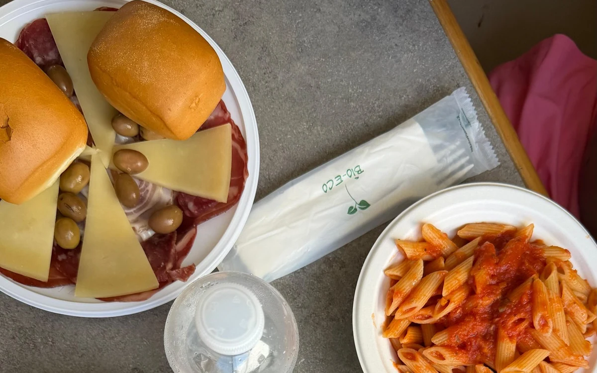 Plates of pasta, cheese and bread rolls seen from above