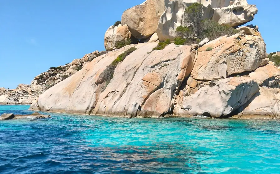 A large weathered granite rock rising from turquoise water