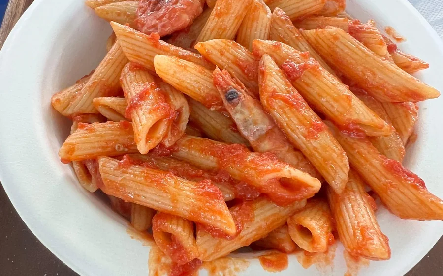 A plate of penne in tomato sauce with a prawn