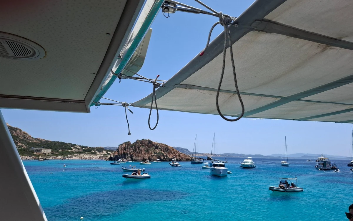 Moored boats and a granite shore seen from under a deck awning