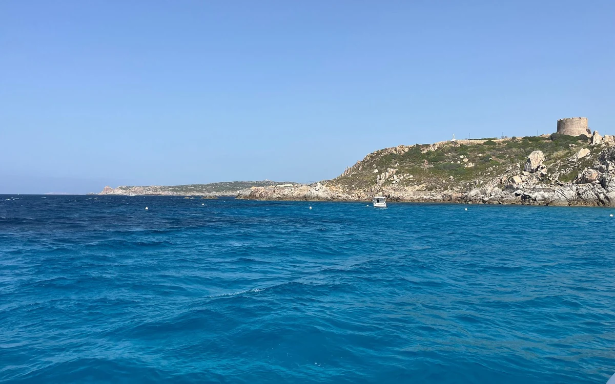 A round stone tower on a granite headland above a deep blue sea